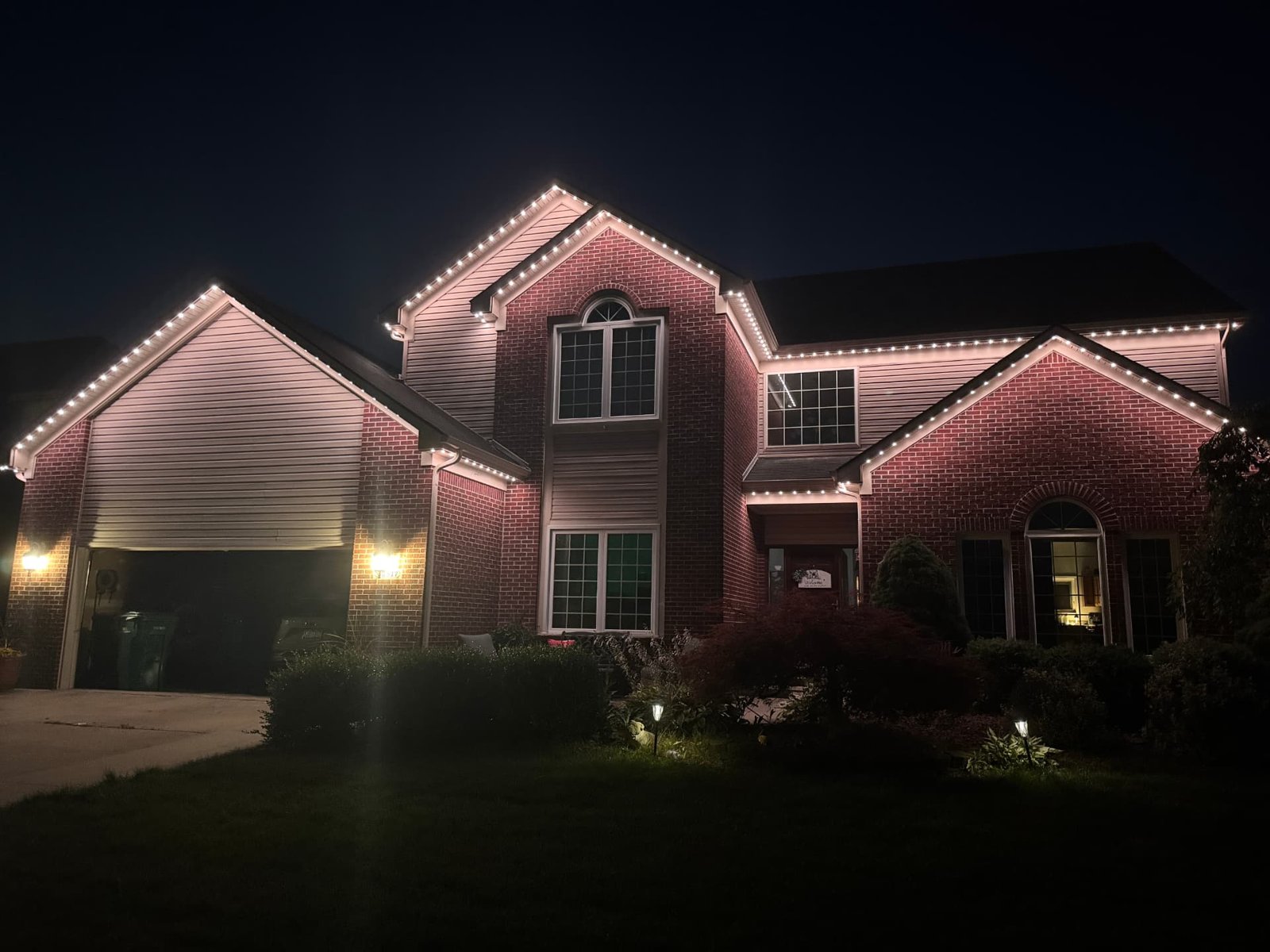 Brick colonial home with warm white permanent LED roofline lighting